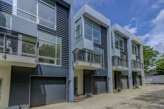 Front view of modern multi-story townhouses with garages and balconies.