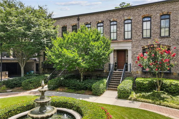 Front view of a brick townhouse with multiple windows and steps leading to the entrance.