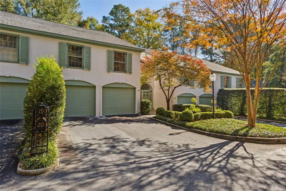 Front view of a multi-unit residential building with garages and green shutters.