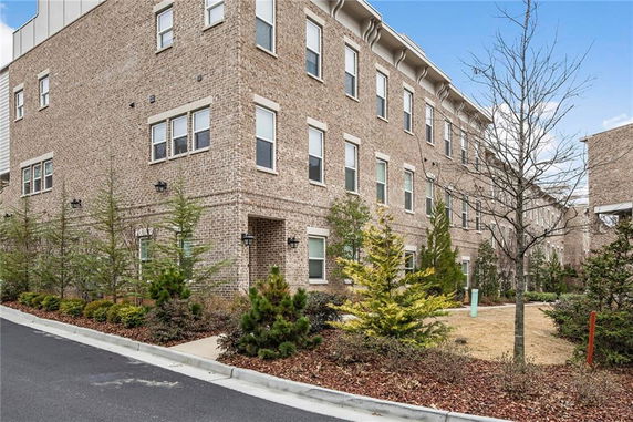 Front view of a multi-story brick building with multiple windows and small landscaped area.