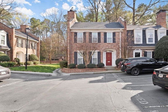 Front view of a two-story brick house with a prominent chimney and a red front door.