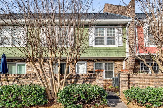 Front view of a two-story townhouse with brick and green siding.