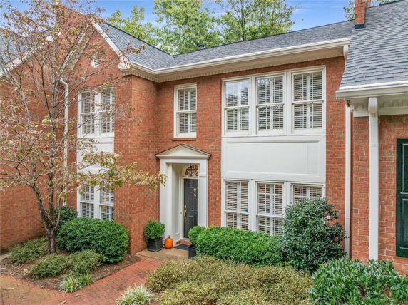 Front view of a two-story brick house with white trim and a central entrance.