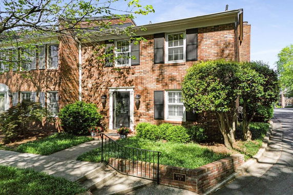 Front view of a two-story brick house with black shutters.