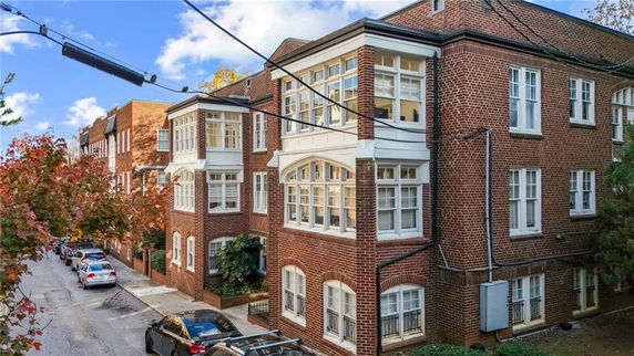 Front view of a multi-story brick building with large windows.