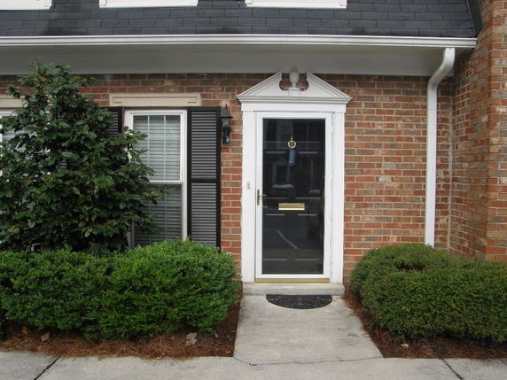 Front view of a brick house with a white door and a small window.