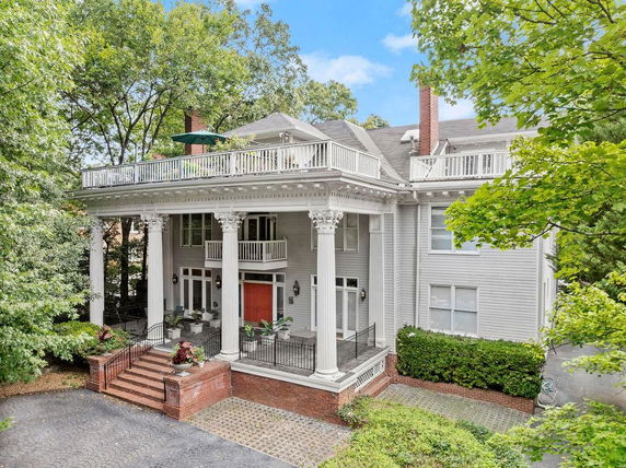 Front view of a large two-story house with tall columns and a balcony.