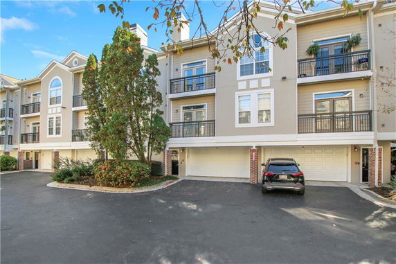 Front view of a multi-story residential building with balconies and garage spaces.