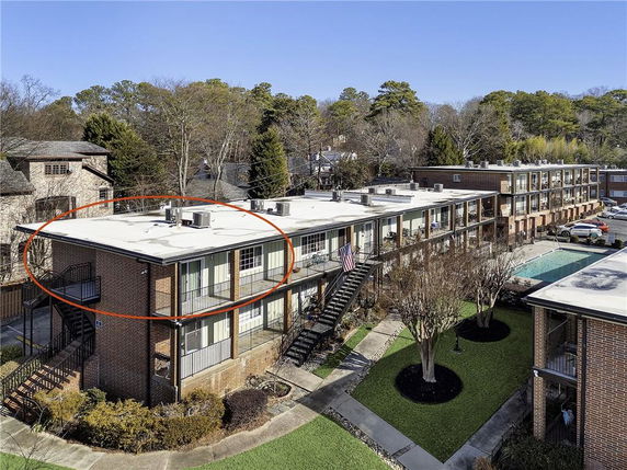 Front view of a multi-story brick apartment building with external staircases and a flat roof.