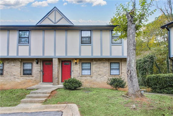 Front view of a two-story townhouse with two red doors and a triangular roof gable.