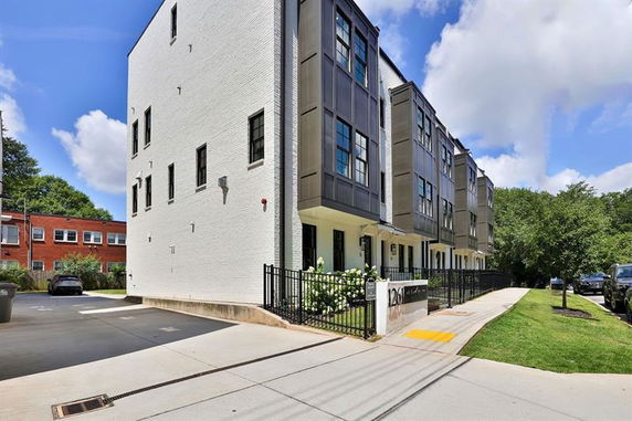 Front view of a multi-story modern townhouse complex with black and white exterior.