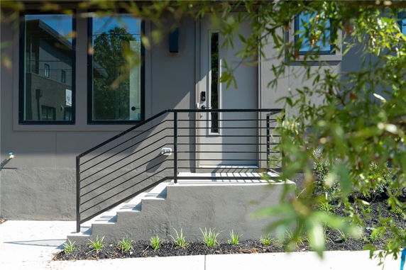 Front view of a modern house entry with steps and railing.