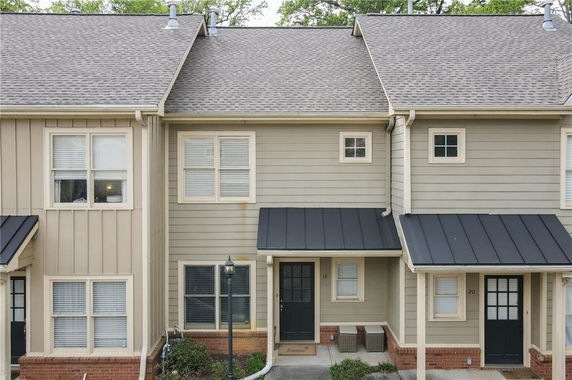 Front view of a townhouse with two stories and a black roof over the entrance.