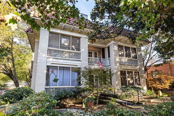 Front view of a two-story house with a screened porch and tile roof.