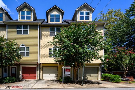 Front view of a three-story townhouse with garages on the ground level.