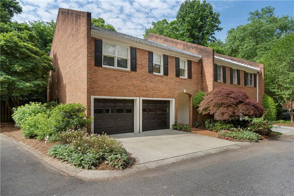 Front view of a two-story brick house with black shutters and a double garage.