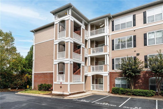 Front view of a multi-story apartment building with balconies and parking area.