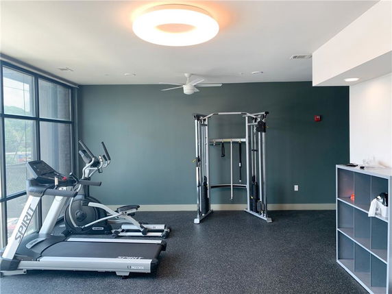 Room equipped with gym exercise machines and large windows.