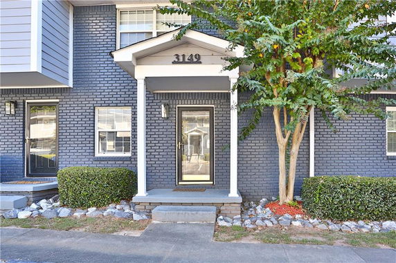 Front view of a townhouse with dark bricks and a white doorframe.