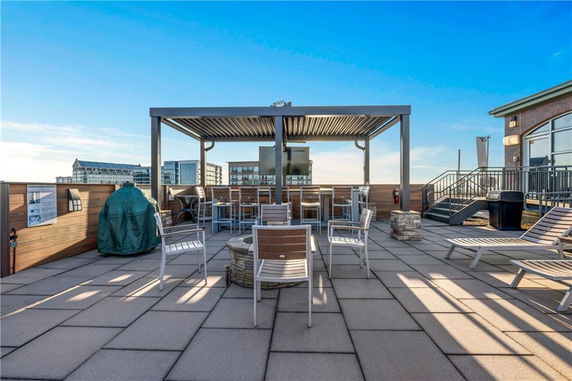 Rooftop area with seating, a grill, and a pergola.
