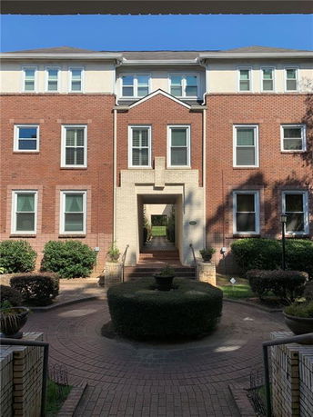 Front view of a three-story brick building with an arched entrance and multiple windows.