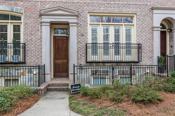 Front view of a brick house with a wooden door and decorative railings.