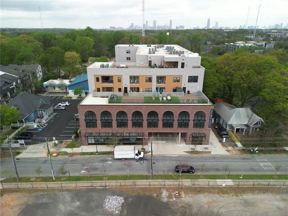 Front view of a multi-story building with a rooftop area and parking below.