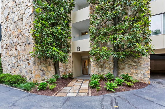 Entrance view of a building with stone facade and trees.