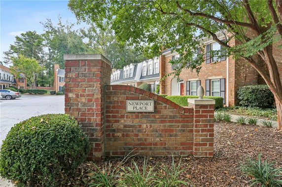 Front view of a multi-story brick townhouse complex entrance with a sign reading 'Newport Place'.