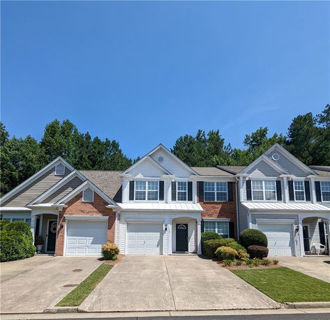 Front view of a row of two-story townhouses with garages and driveways.