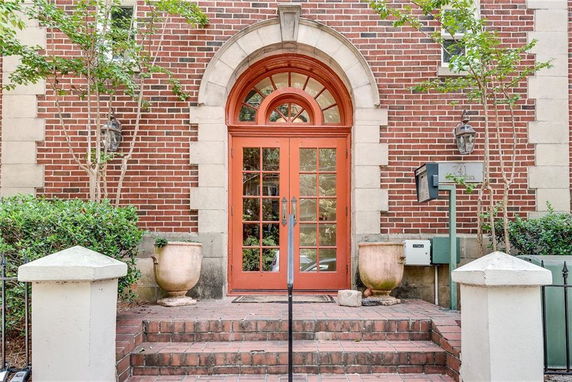 Front view of a brick building entrance with arched doorway and steps.
