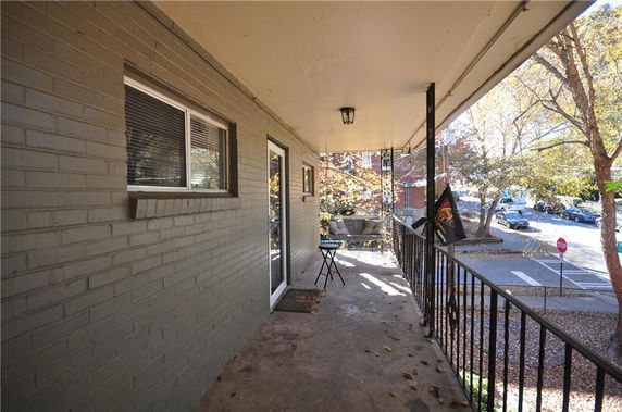 View of a building entrance with a balcony and surrounding street area.