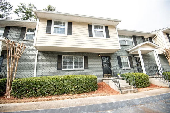 Front view of a two-story townhouse with a brick exterior and small porch.