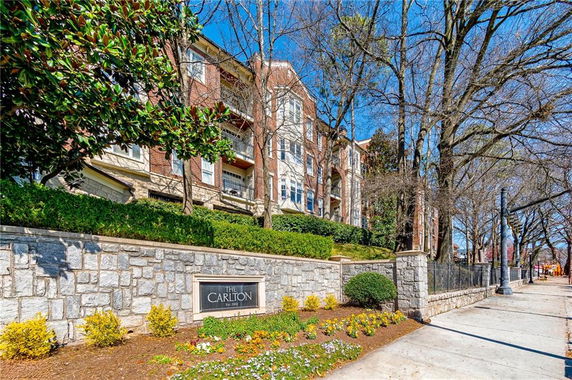 Front view of a multi-story residential building with brick facade and stone perimeter wall.