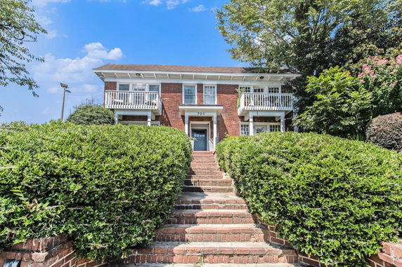 Front view of a two-story brick house with a central entrance and balconies on both sides.