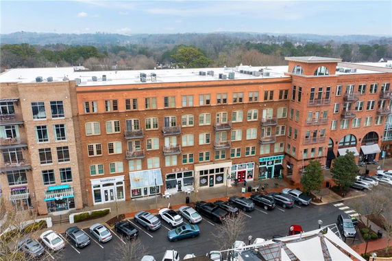 Front view of a multi-story brick building with shops on the ground floor and balconies on upper floors.