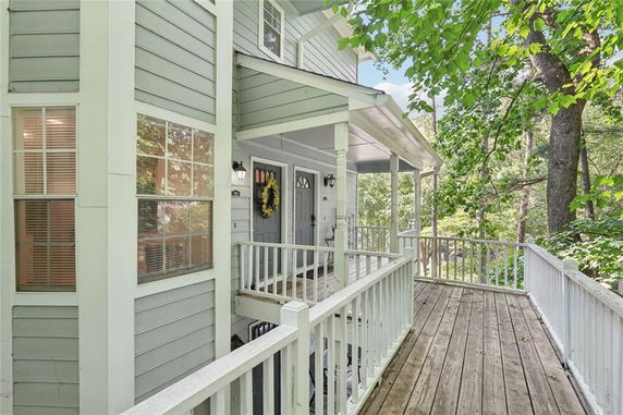 Front view of a multi-story house with a wraparound porch and white railing.