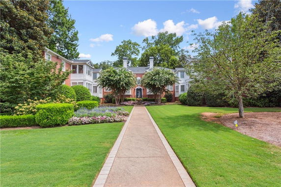 Front view of a large, multi-story house with a symmetrical design and landscaped pathway.