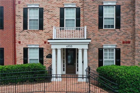 Front view of a brick house with black shutters and white columns.