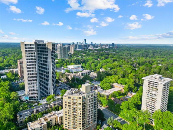 Panoramic view of tall residential buildings with a city skyline and surrounding greenery.