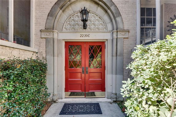 Front view of a house entrance with double red doors and an arched stone frame.