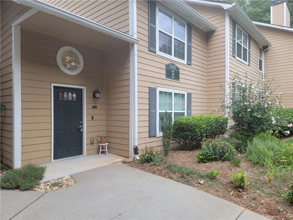 Front view of a two-story house with beige siding and a black door.