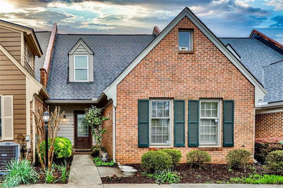 Front view of a brick house with gable roof and dormer window.
