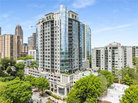 Front view of a tall modern residential building with glass exteriors in an urban area.