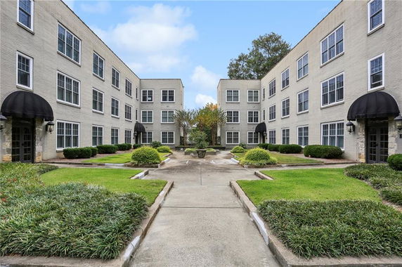 Front view of a three-story building with multiple windows and landscaped courtyard.