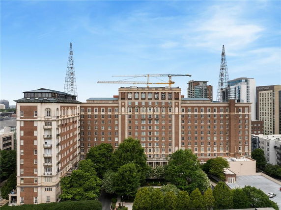 Front view of a large multi-story building with construction cranes in the background.