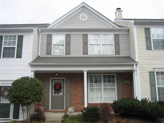 Front view of a two-story townhouse with a brick facade and gray shutters.