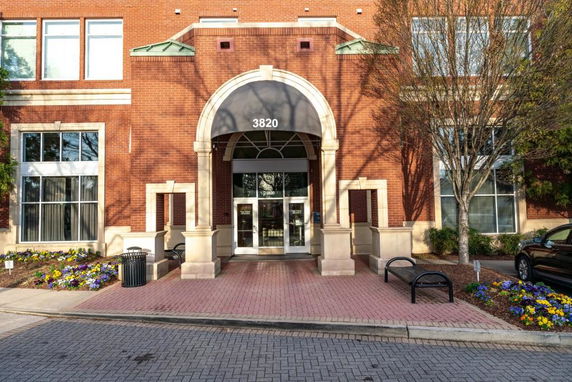 Front view of a brick building with an arched entrance and large windows.