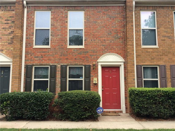 Front view of a two-story brick townhouse with a red door.