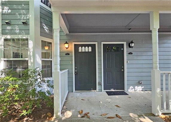 Front view of a residential building entrance with two doors, porch pillars, and outdoor lighting.